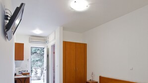A bedroom with a wooden bed, a bedside table, a small desk with a chair, and a wardrobe. - Porto Assini (Nafplio)