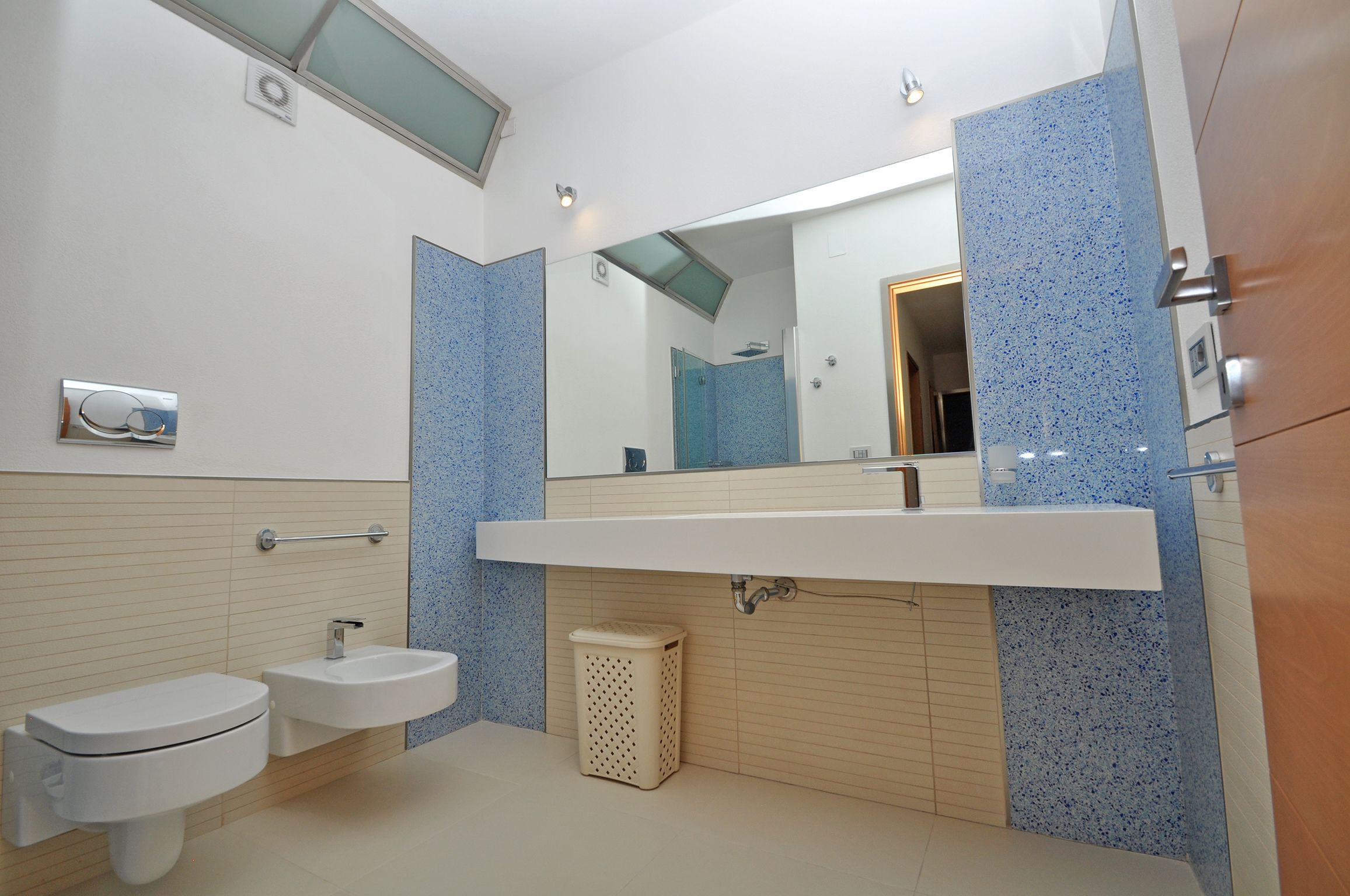A modern bathroom with a white sink, a toilet, and a mirror.