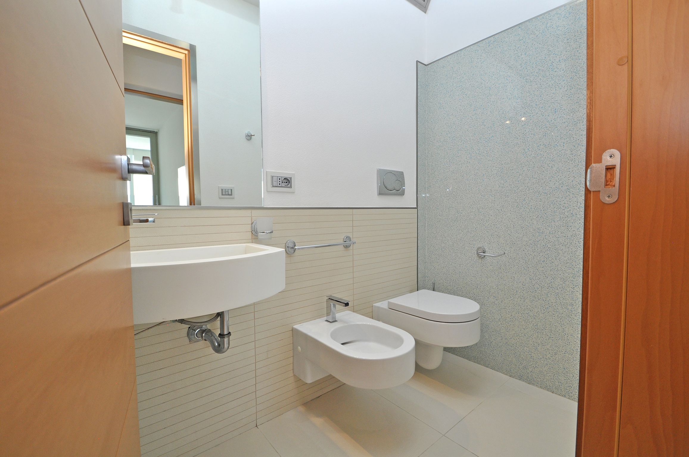 A modern bathroom with a sink, toilet, and bidet.