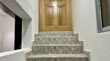 A set of stone-tiled stairs leading to a wooden door.