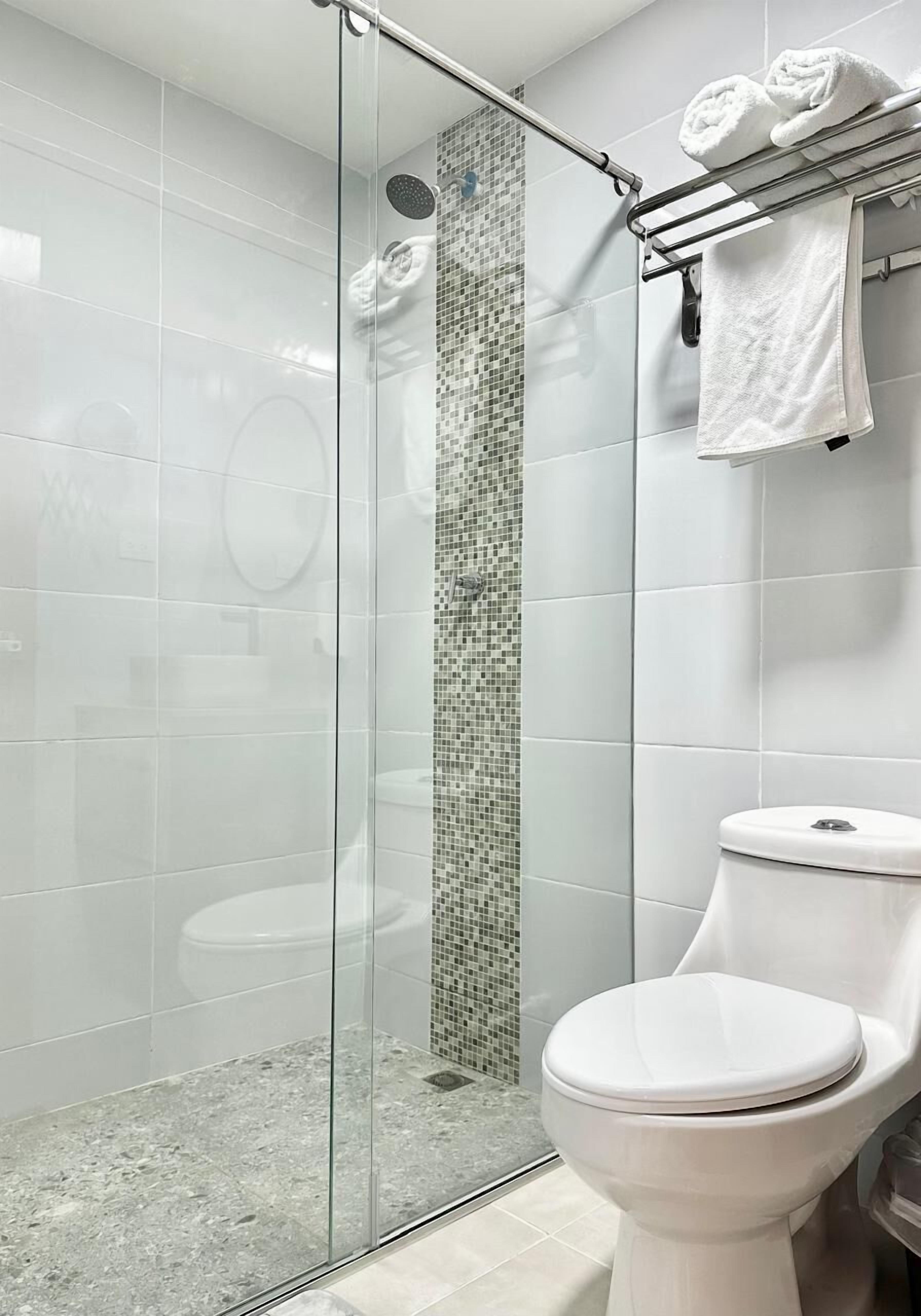 Ein modernes Badezimmer mit einer einachigen Duschkabine, Toilette und einem Handtuchhalter mit gefalteten Handtüchern.