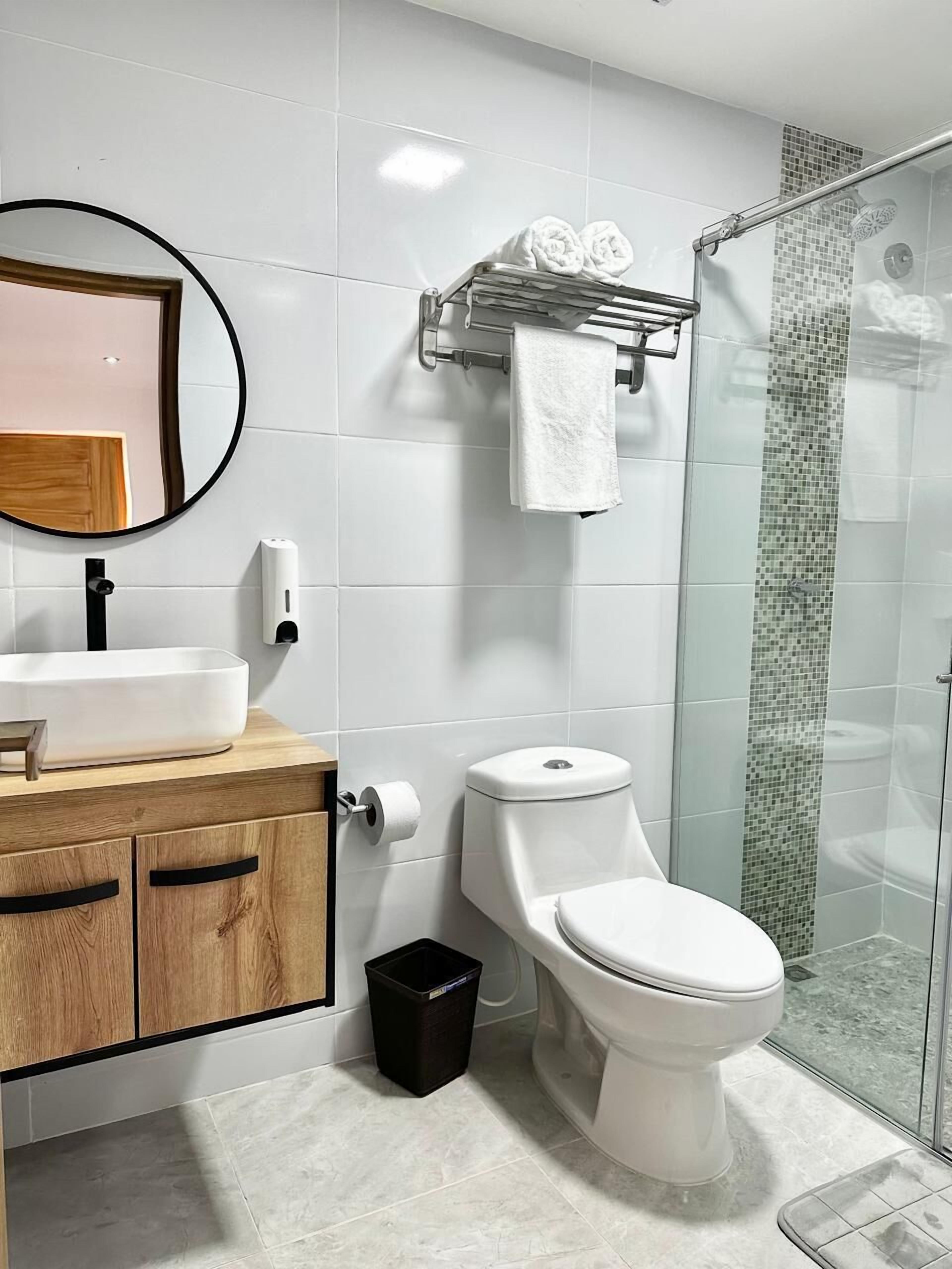 Une salle de bain moderne avec un lavabo blanc, un meuble en bois, des toilettes et une cabine de douche en verre.