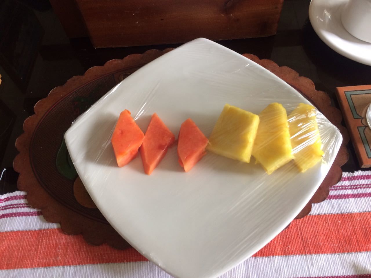 Un plato blanco con frutas cortadas sobre un camino de mesa.