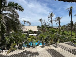 A resort with a pool, palm trees, and a view of the ocean. - Casa Berastegui (Puerto Colombia)
