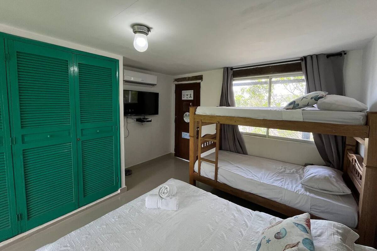 A room with bunk beds, a television, and a green wardrobe.