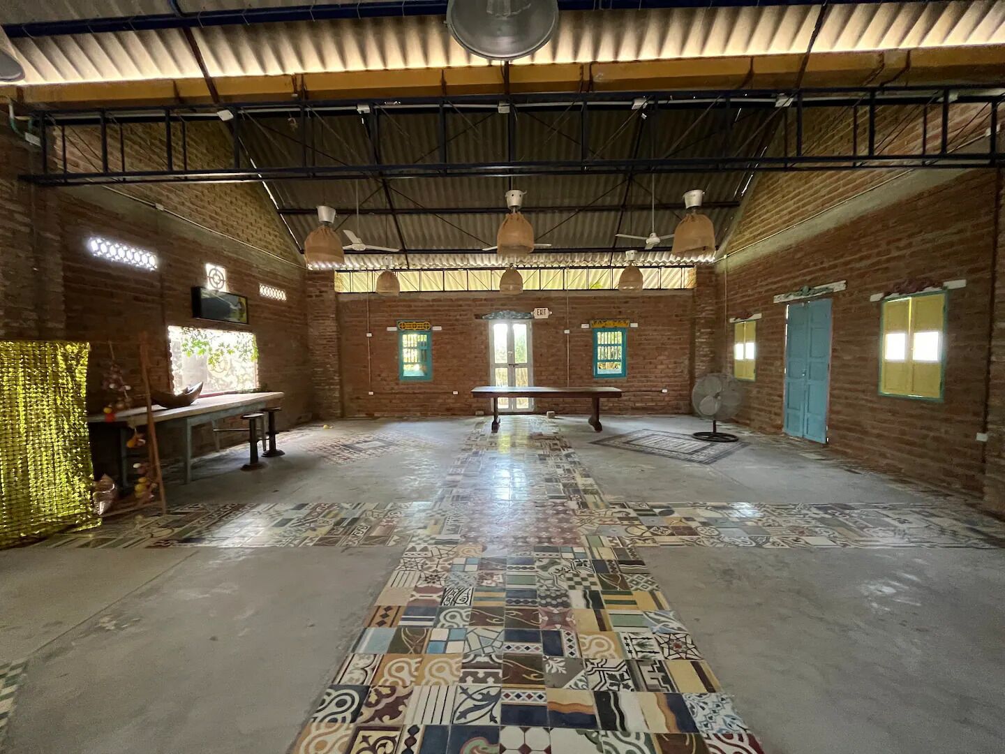 Una habitación amplia con piso estampado, paredes de ladrillo y un techo alto con vigas a la vista.