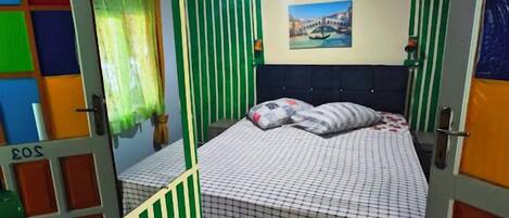 Una habitación con cama, espejo y ventilador de techo.