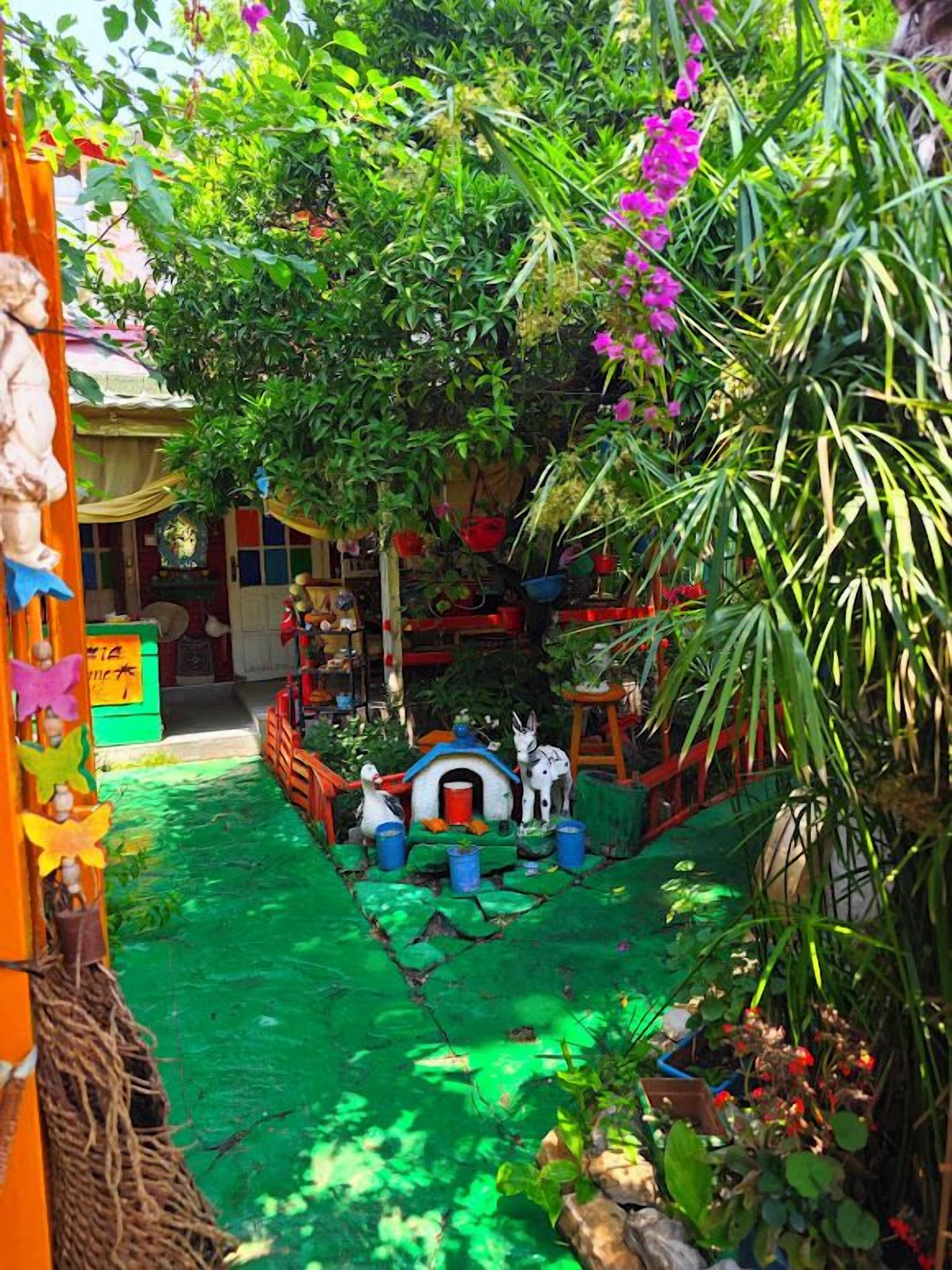 A vibrant indoor garden with a small animal house, lush greenery, and a colorful pathway.
