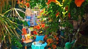 Ein Garten mit Tisch und Stühlen, umgeben von viel Grün und Blumen.