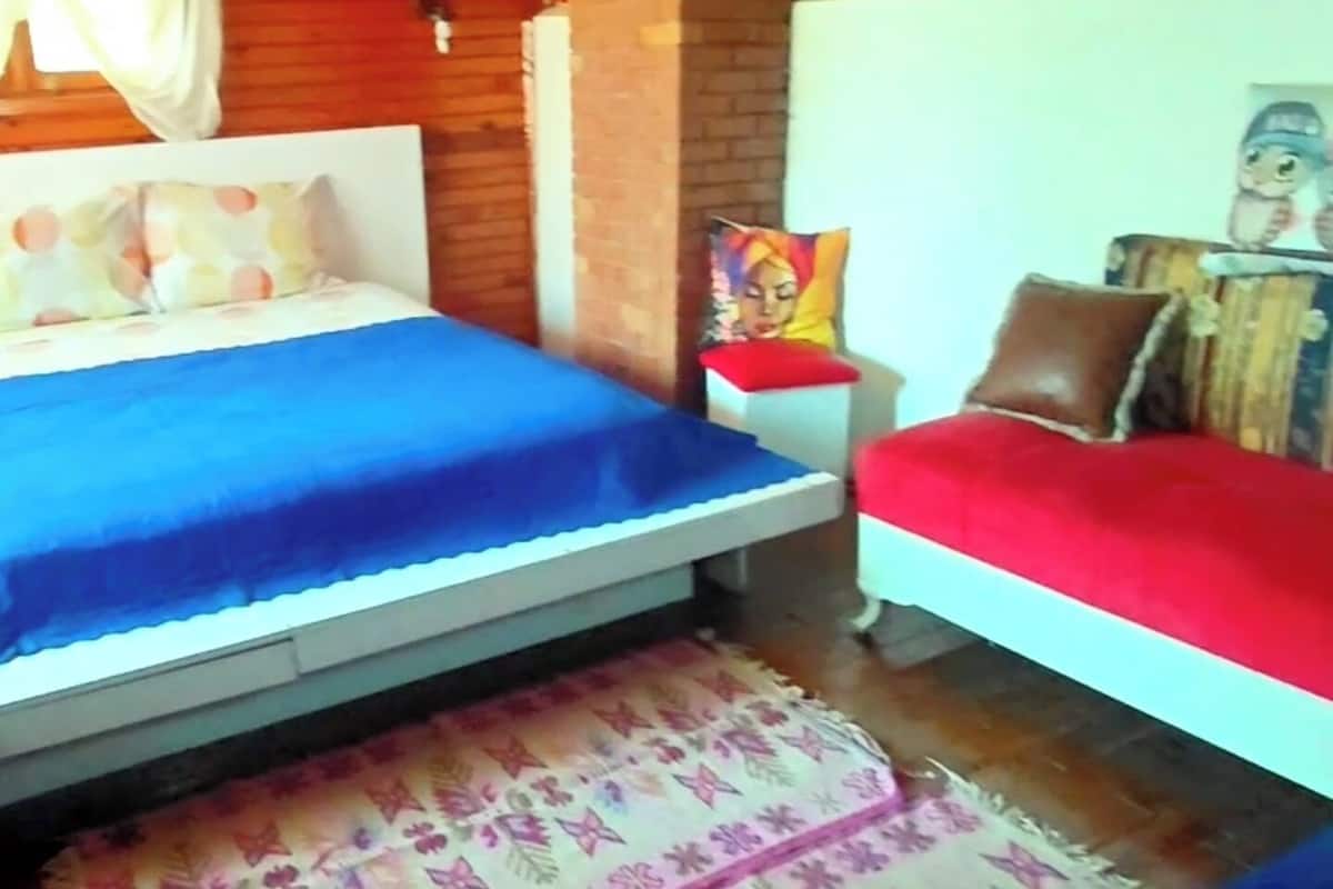 A wooden-paneled room with two beds, a patterned rug, and a wall with artwork.