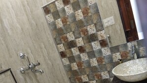 Een badkamer met een douche, toilet, wastafel en een decoratieve betegelde muur.