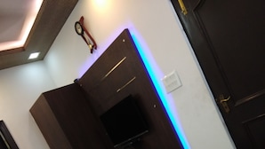Een slaapkamer met een bed, een televisie aan de muur en een deur met een handgreep.