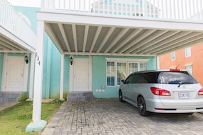 A two-story building with a covered driveway and a parked car.