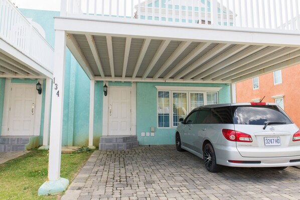 A two-story building with a covered driveway and a parked car. - Paradise at Little Bay Cournty Club (Negril)