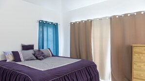 A bedroom with a bed, a dresser, and curtains. - Paradise at Little Bay Cournty Club (Negril)