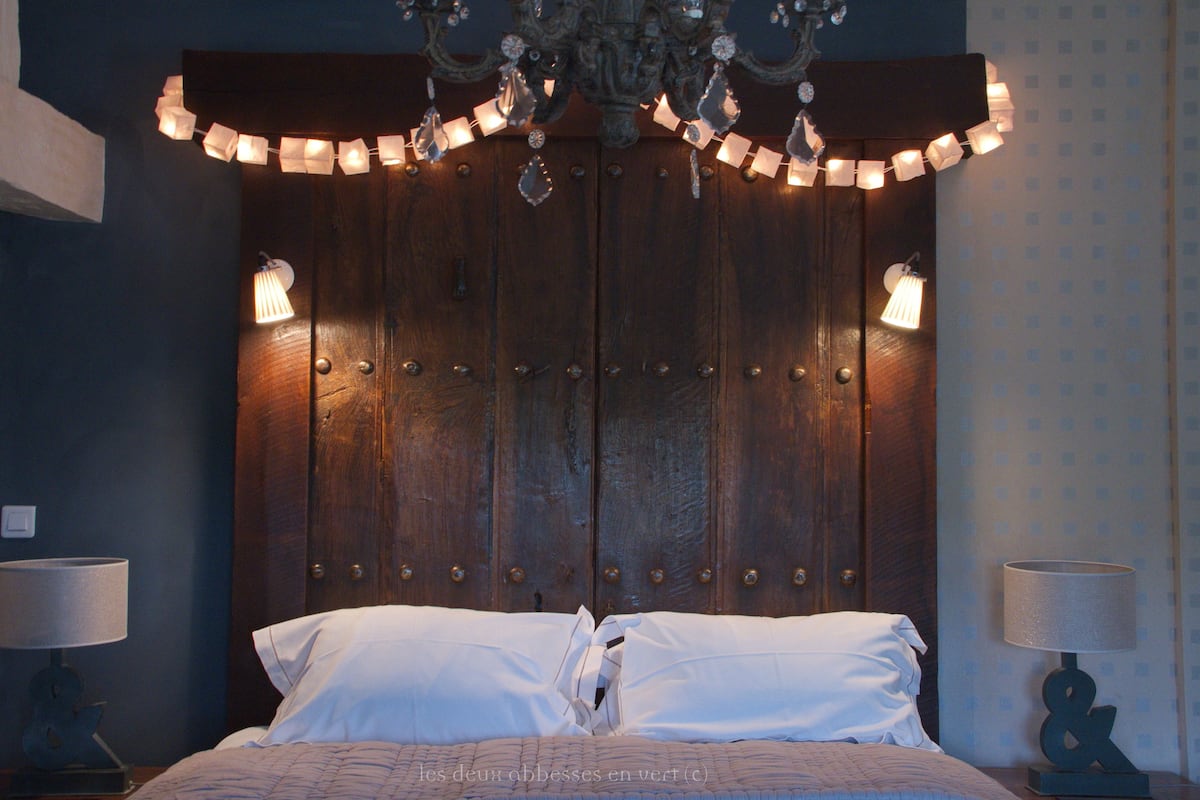 Une chambre à coucher avec une tête de lit en bois, deux lampes de chevet et un lustre.