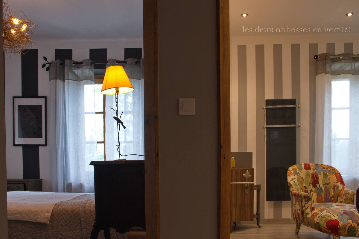 Une chambre d’hôtel avec un lit, une lampe, une chaise et une fenêtre avec des rideaux.