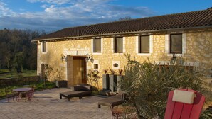 A stone building with a tiled roof, a patio with outdoor furniture, and a garden area. - Les Deux Abbesses en Vert (Mareuil en Périgord)