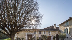A stone building with a courtyard, a large tree, and outdoor seating. - Les Deux Abbesses en Vert (Mareuil en Périgord)