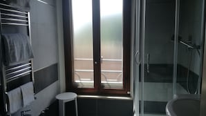 A modern bathroom with a glass shower enclosure, a sink, and a toilet. - Camollia Suites (Siena)