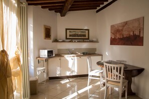 A small kitchen with a microwave, sink, and a dining area with a table and chairs. - Camollia Suites (Siena)