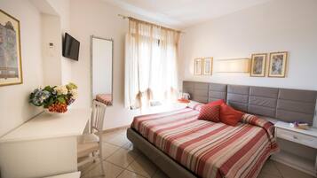 Une chambre d’hôtel comprenant un lit, une table de chevet, une chaise, un bureau et un téléviseur.