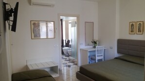 A bedroom with two beds, a desk, and a chair. There is a door leading to another room. - Camollia Suites (Siena)