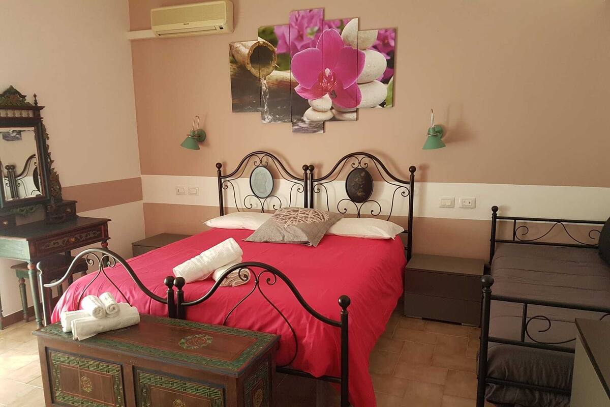 A bedroom with a bed, a nightstand, a dresser, a mirror, and a wall-mounted picture.
