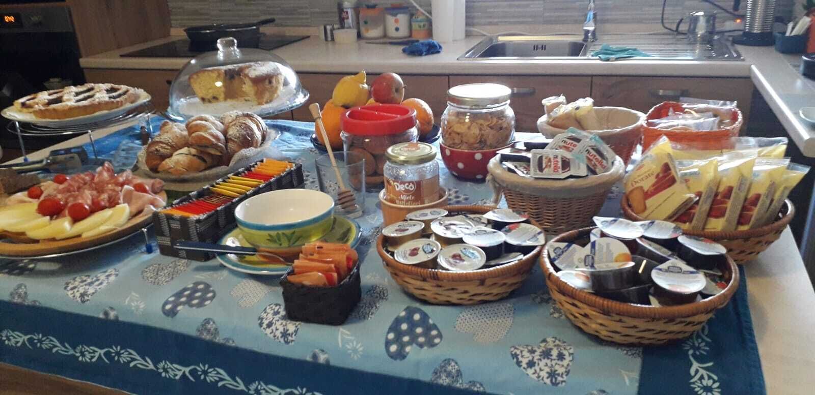A buffet table with various food items including pastries, fruits, and condiments.