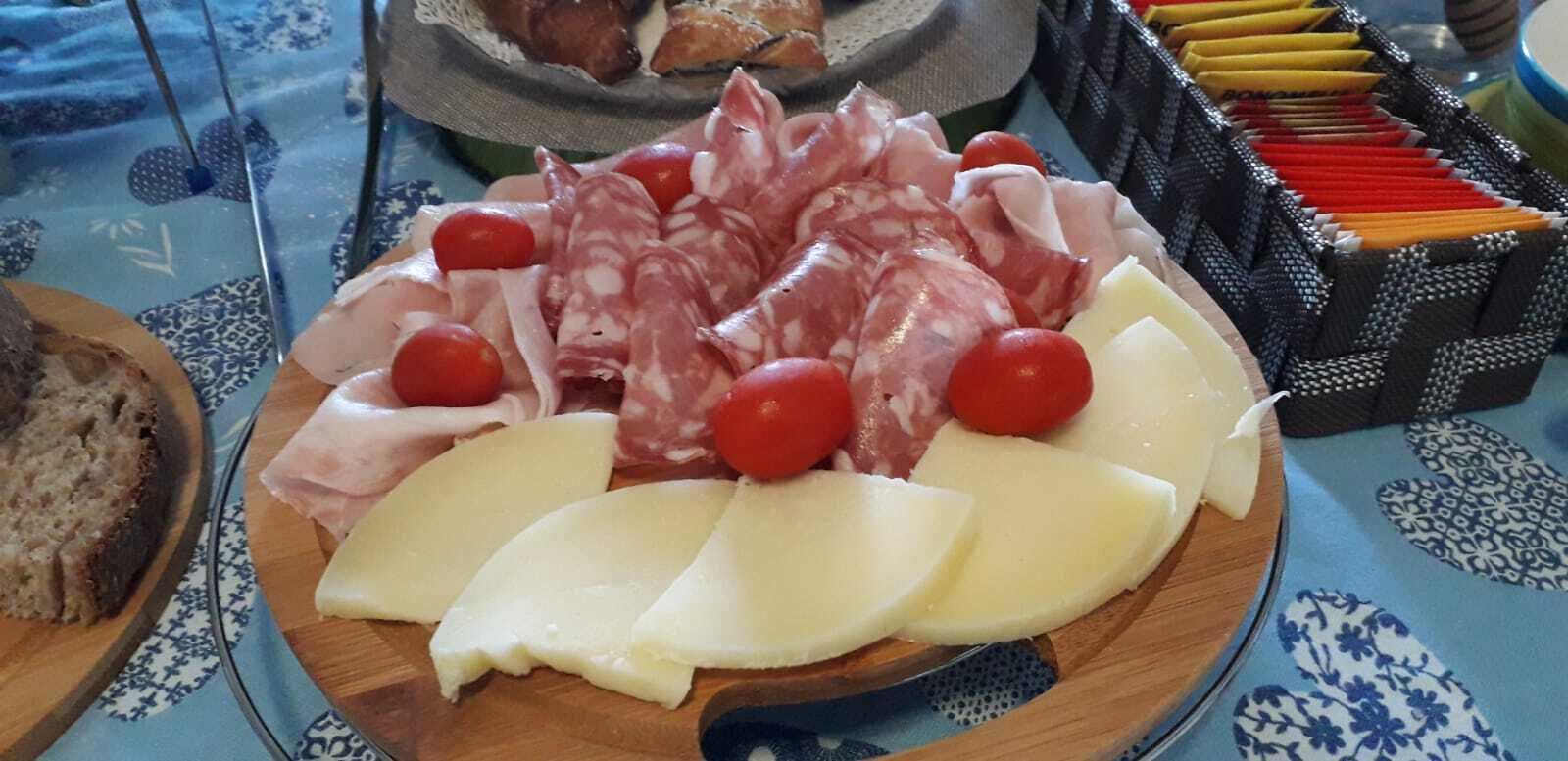 A charcuterie board with various meats, cheese, and cherry tomatoes.