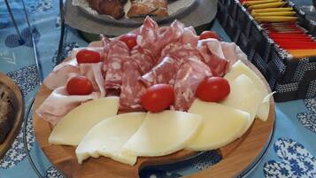A charcuterie board with various meats, cheese, and cherry tomatoes.