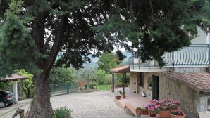 A stone building with a tiled roof, a covered patio area with potted plants, and a stone pathway leading to the entrance. - Bed & Breakfast Villa Flora (Agropoli)