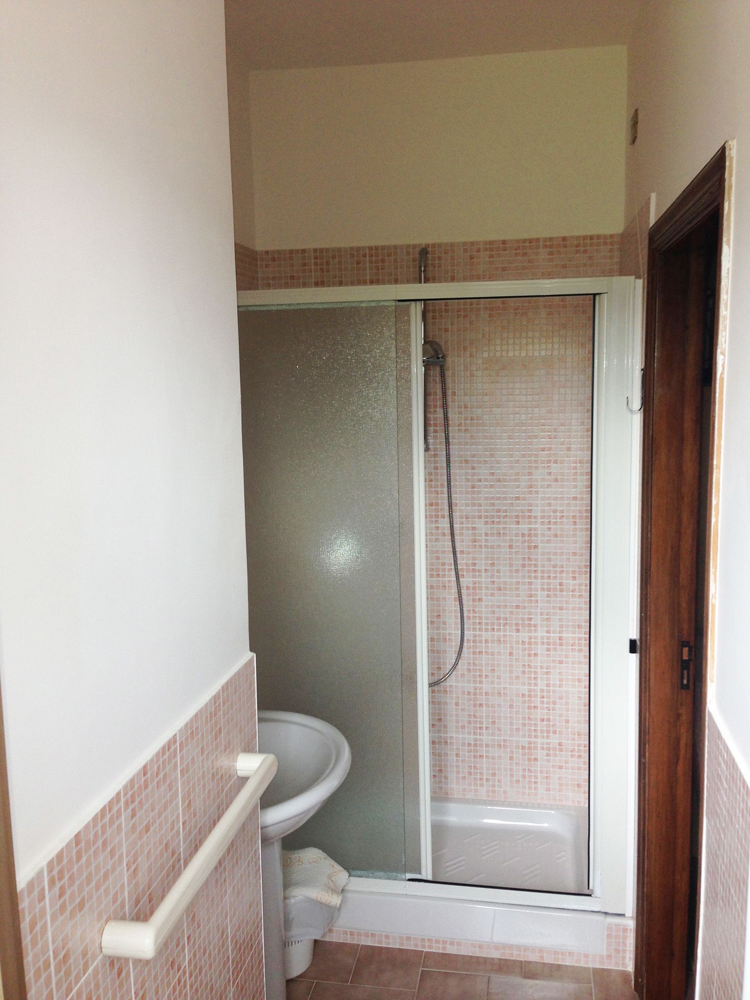 Een badkamer met douche, toilet en wastafel.