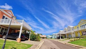 A residential street with houses, a clear sky, and a parked car. - Tropics at Little Bay Country Club (Negril)