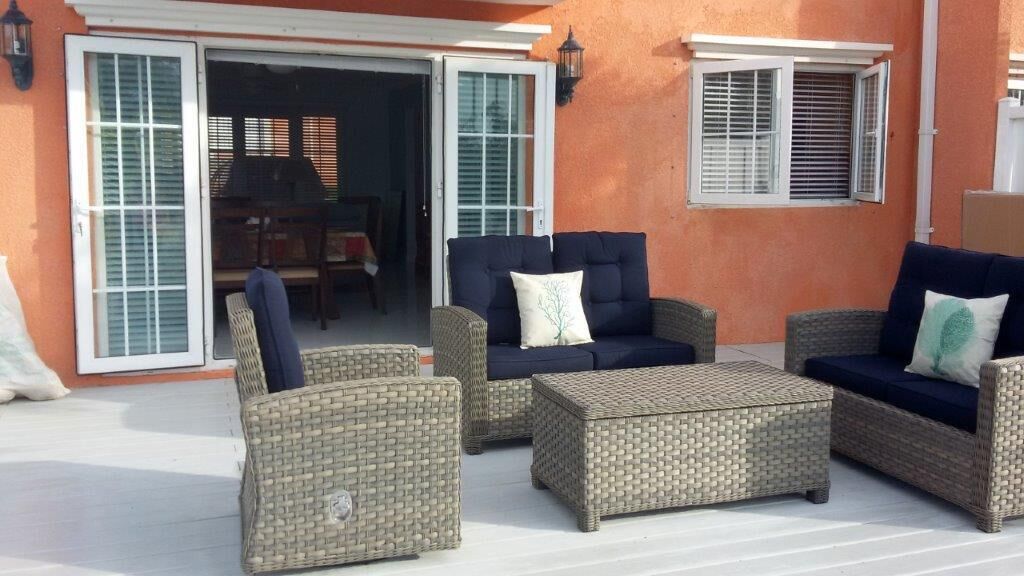 An outdoor patio area with wicker furniture, including sofas and a coffee table.