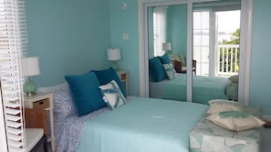 A bedroom with a large bed, a nightstand, a lamp, and a sliding glass door leading to a balcony. - Tropics at Little Bay Country Club (Negril)