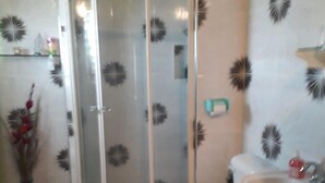 Baño con cabina de ducha, inodoro, lavamanos y diseños decorativos en la pared.