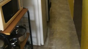 Una cocina compacta equipada con refrigerador, microondas y un lavamanos pequeño.
