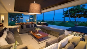 Ein modernes Wohnzimmer mit großem Fenster und Ausblick auf eine schöne Landschaft, ausgestattet mit Deckenventilator und Essbereich mit Tisch und Stühlen.