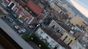 A cityscape with a mix of residential and commercial buildings, a busy street with cars, and a cloudy sky. - Harmony Rooms (Catania)