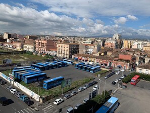 A parking lot with multiple buses and cars, surrounded by buildings with varied architecture. - Harmony Rooms (Catania)