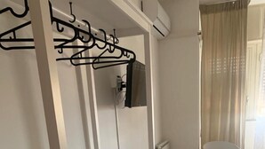 A hotel room with a white wardrobe, a black chair, a small table, and a marble floor. - Harmony Rooms (Catania)