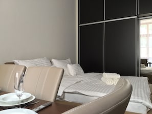 Een hotelkamer met een bed, een eettafel met borden en bestek, en een afstandsbediening.