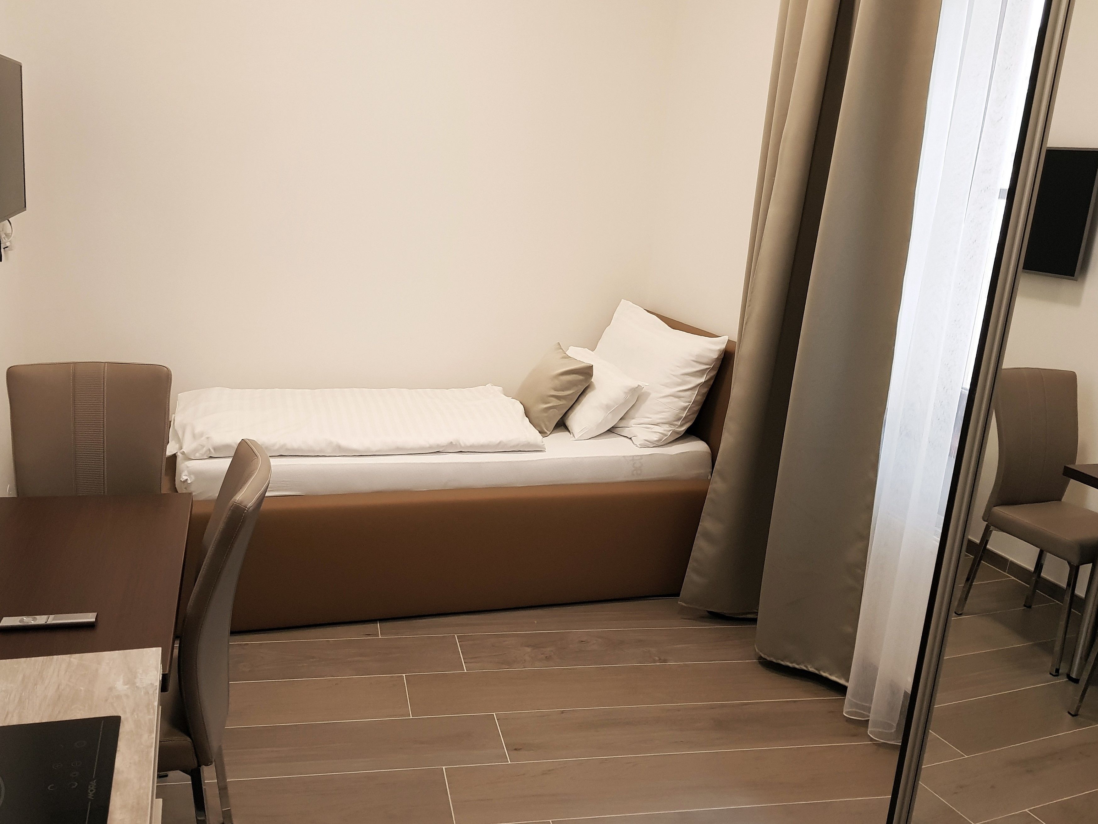 Una habitación compacta con cama, una mesita y una silla.