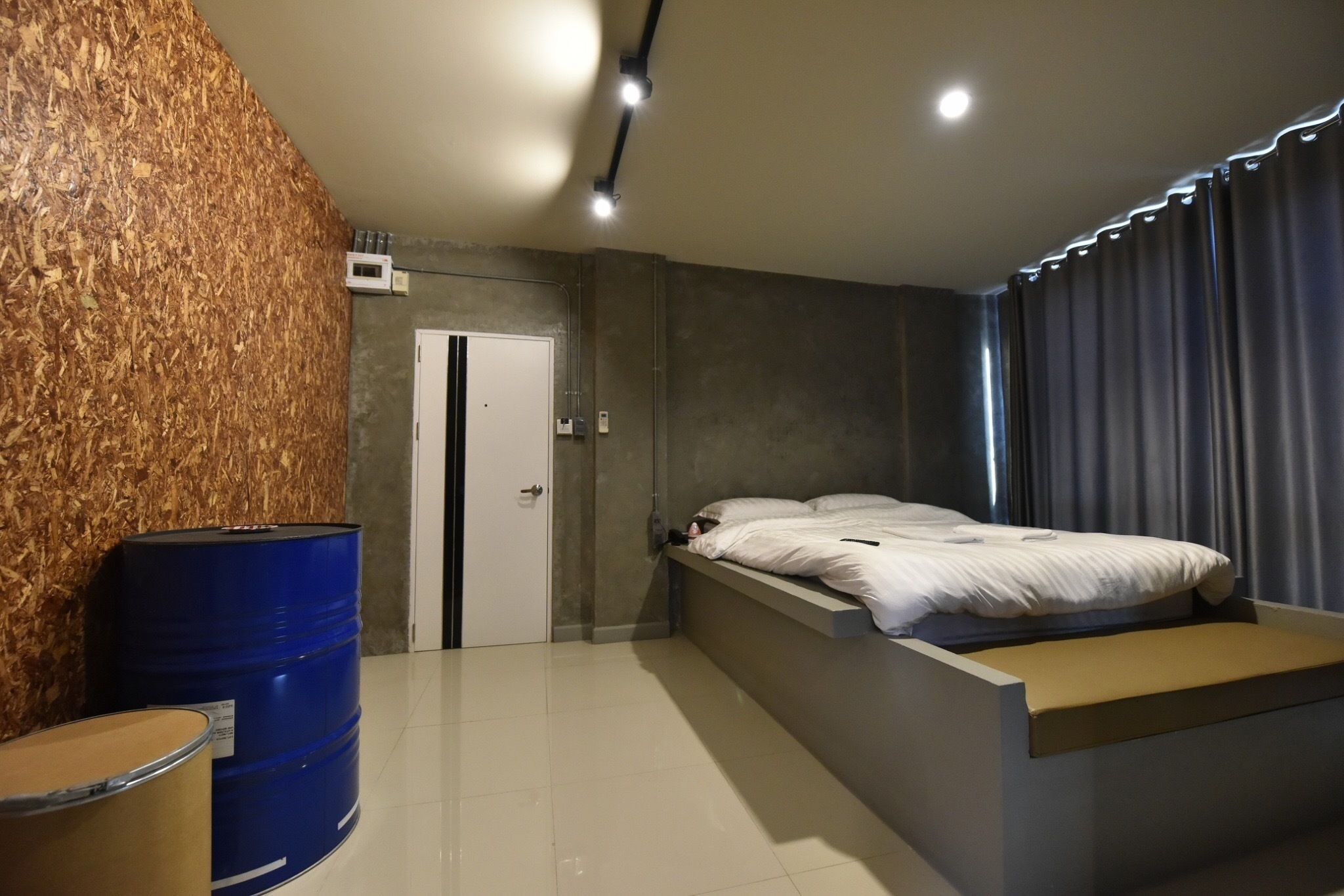 Een moderne slaapkamer met een inbouwed bed, een houten accentmuur en een groot raam met gordijnen.