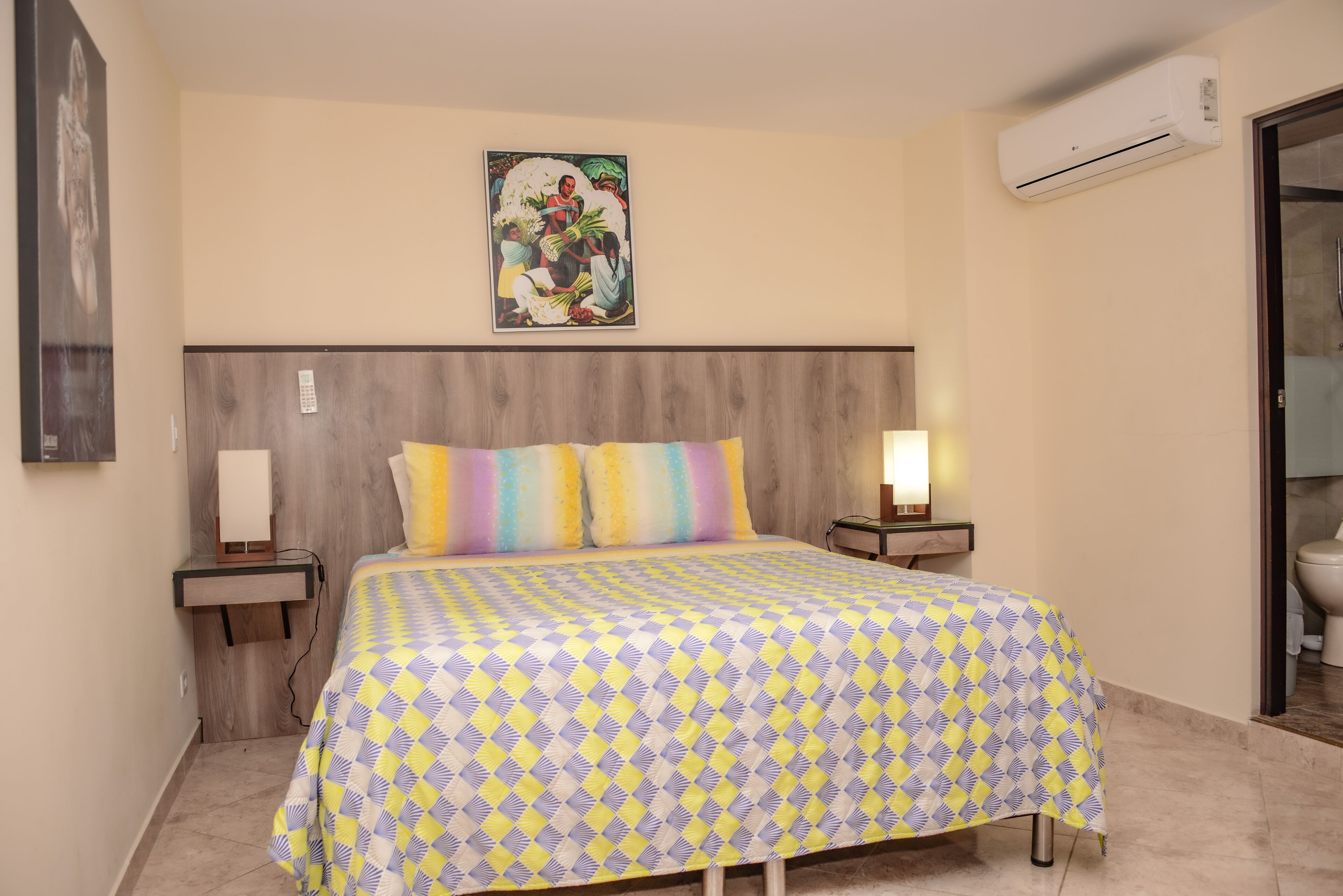 A bedroom with a bed, a nightstand, a wall-mounted air conditioner, and a poster on the wall.