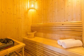 A wooden sauna with benches, a bucket, and towels.