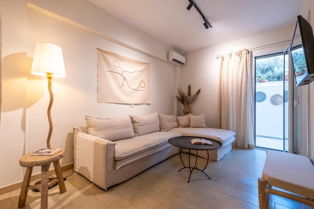 A modern living room with a sofa, a small table, a lamp, and a flat-screen TV.
