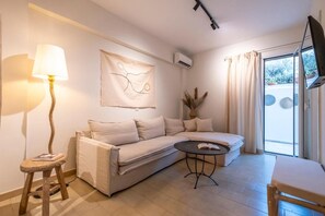 Ein modernes Wohnzimmer mit einer Couch, einem kleinen Tisch, einer Lampe und einem Flachbildfernseher.