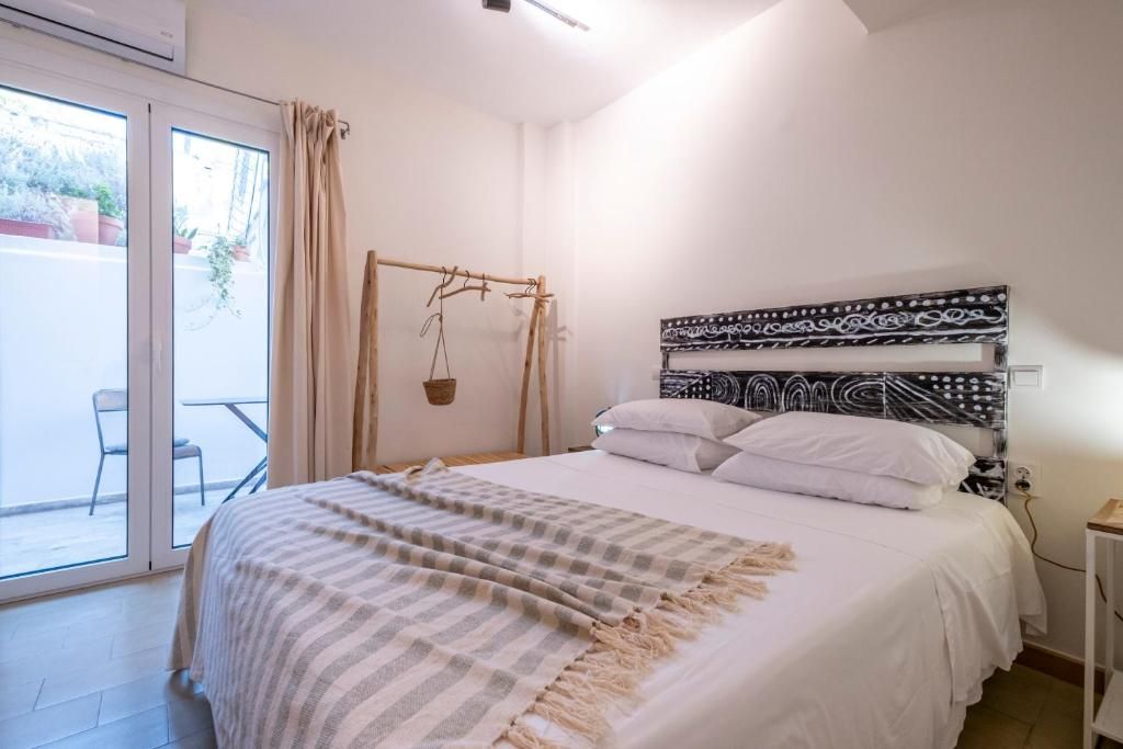 A bedroom with a bed, a hanging basket, a window with curtains, and a view of the outside.
